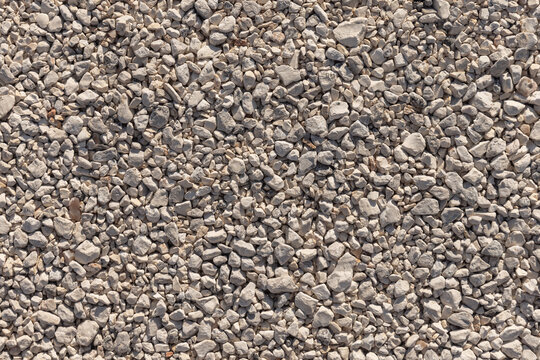 Closeup aerial view of light-colored gravel forming a textured background ideal for landscaping, pathways, construction aggregate and natural material design. Background photo texture
