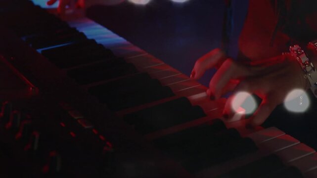 Animation on blurred night road traffic over hands of caucasian man playing keyboard on concert