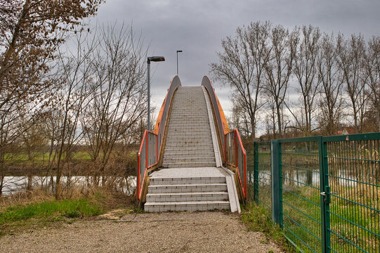 Perspektivischer Blick &uuml;ber die Katzenbuckelbr&uuml;cke in die Saale-Aue bei Leuna, moderne Fu&szlig;g&auml;ngerbr&uuml;cke mit orangefarbenem Gel&auml;nder, Infrastruktur und Naherholung, Sachsen-Anhalt, Deutschland