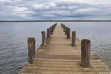 Fototapeta premium Hölzerner Bootssteg Löptitzer Steg am Wallendorfer See bei bewölktem Himmel, malerische Seenlandschaft und Naherholungsgebiet im Saalekreis, Burgliebenau, Schkopau, Sachsen-Anhalt, Deutschland