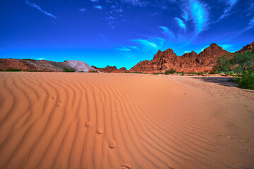 Fototapeta premium Sand Dune Patterns Red Rock Mountains and Dramatic Sky Nevada Desert Landscape