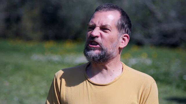 Close-Up of Angry Bearded Man Growing Increasingly Furious in Nature. 