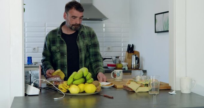Morning meal preparation: A focused individual in a home kitchen is meticulously preparing a breakfast, with fresh fruits arranged on a counter alongside other food items.