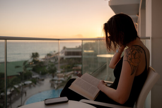 A woman reading a book on a balcony at a hotel on Sint Maarten island in the Caribbean Sea.