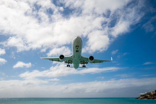 An airplane landing over Maho Beach on Sint Maarten island in the Caribbean Sea.