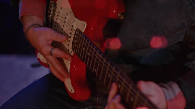 Musician plucking strings as camera tightening on red guitar, bokeh accenting melody for music demo
