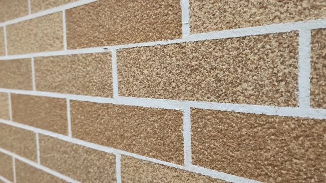 Close-up of decorative brick-patterned facade texture. Professional horizontal pan of brown mosaic plaster wall. architectural finishing material.