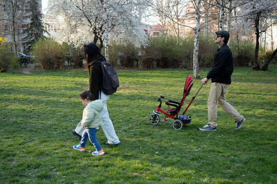 A young family walking on the grass in the park with their daughter on a spring day