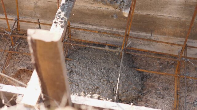 Concrete Flowing From Chute Into Reinforcement Grid And Rebar Cage, Closeup Of Mixture Texture Settling Into Form, Crew Preparing Next Section While Maintaining Steady Flow