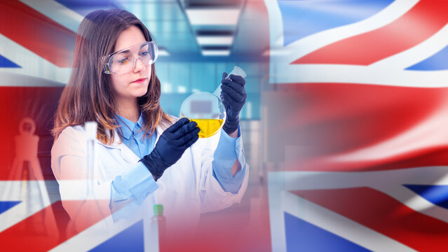Chemical research, Laboratory science. Female scientist analyzes liquid sample in glass flask, conducting chemical testing and fuel research in a modern UK laboratory.