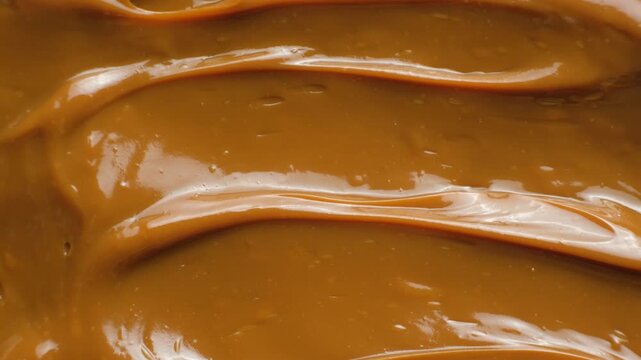 Stirring thick boiled condensed milk with a spoon close up.