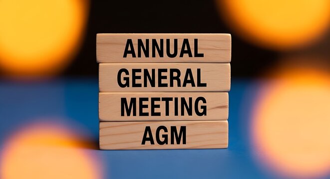 Annual General Meeting AGM text on wooden blocks with blurred lights.