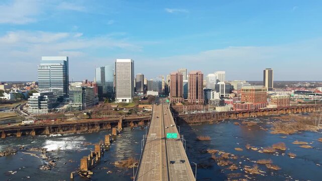 Richmond, Virginia skyline featuring the Manchester Bridge crossing the James River rapids into the downtown financial district. 4k aerial cinematic video.