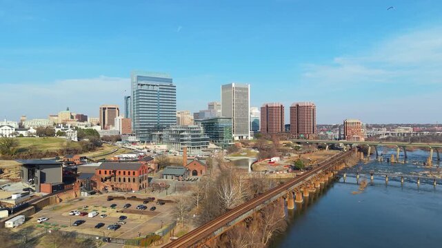 Richmond, Virginia skyline featuring the Manchester Bridge crossing the James River rapids into the downtown financial district. 4k aerial cinematic video.