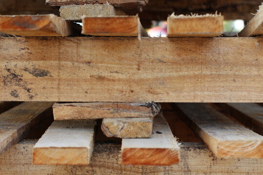 Close-up view of stacked rough wooden planks with visible grain and texture