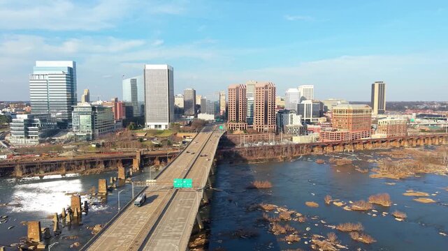 Richmond, Virginia skyline featuring the Manchester Bridge crossing the James River rapids into the downtown financial district. 4k aerial cinematic video.