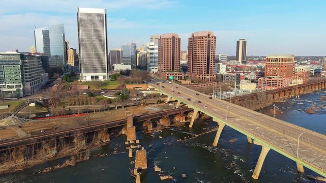 Richmond, Virginia skyline featuring the Manchester Bridge crossing the James River rapids into the downtown financial district. 4k aerial cinematic video.
