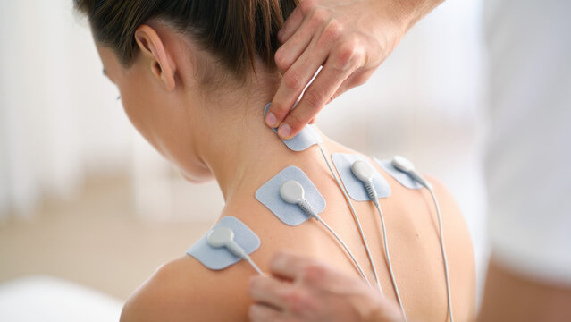Transcutaneous electrical nerve stimulation therapy for pain management in physiotherapy rehabilitation session using electrode pads on patient skin
