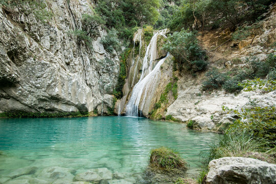 Idyllischer Wasserfall in felsiger Schlucht mit t&uuml;rkisblauem See im Urlaub 