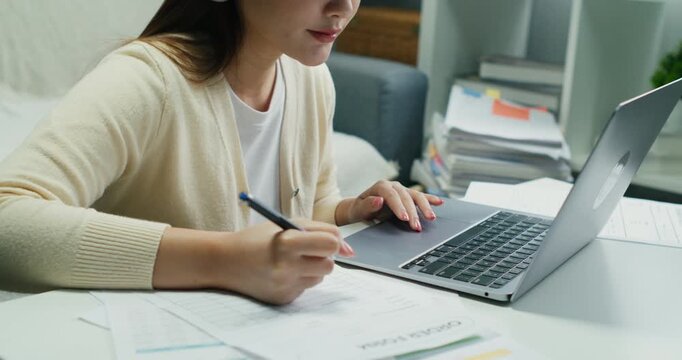 An Asian professional at her desk, using technology for corporate connection and communication. A hybrid job in her modern interior workplace.