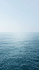 Fototapeta premium Minimalist ocean view, soft pale water and sky, misty horizon, large negative space.