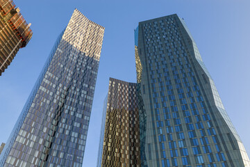 Obraz premium A low-angle shot looking up at the glass facades of the Deansgate Square towers in Manchester UK at Sunrise. 
