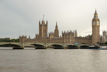 The Gothic Revival splendor of the Palace of Westminster dominates the horizon, its intricate spires and golden limestone facades reflected subtly in the undulating surface of the River Thames. To the