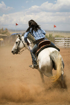 Galisteo Rodeo, New Mexico, United States. Barrel racing horse and rider navigating turn around barrel in rodeo arena