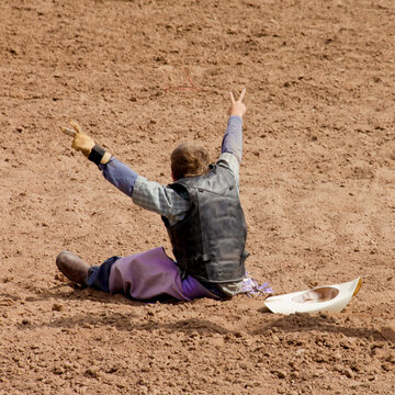 Galisteo, New Mexico, United States. Young rodeo rider sitting in arena after fall during steer riding event
