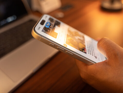 Scrolling social media feed mindlessly, indoor room illuminated by warm tone light. Digital addiction and mindless content consuming in Bangalore, India, on February 28, 2026