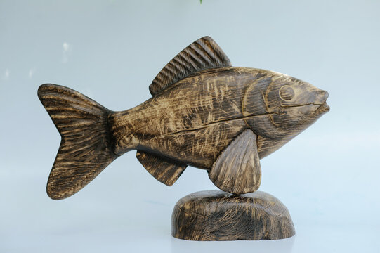 Hand-carved wooden fish sculpture on a natural stone-shaped wooden base, showcasing the detailed head and deep distressed timber grain.
