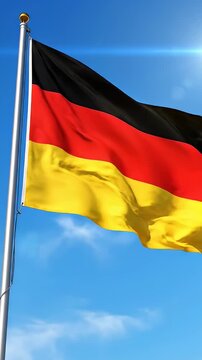 German Flag Waving Against Blue Sky - The German flag waves proudly against a clear, bright blue sky. The flag features the colors black, red, and gold.