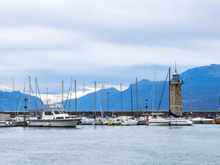 Fototapeta premium Garda lake, Italy. Lighthouse in the port of Desenzano del Garda. Yachts and boats moored in the port.