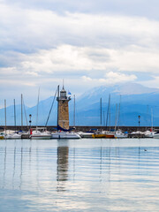 Fototapeta premium Garda lake, Italy. Lighthouse in the port of Desenzano del Garda. Yachts and boats moored in the port.