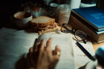 Naklejka premium A messy home office desk with a half-eaten sandwich, a coffee rings on a notebook, and a pair of blue-light glasses. Direct flash photography, 35mm film grain, slightly out of focus, realistic skin te