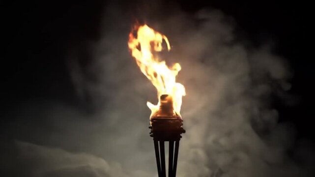 A dramatic video of a torch burning brightly in the darkness with smoke swirling around it