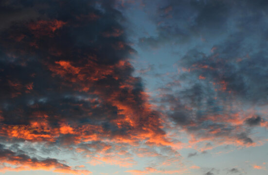 Red and purple rain clouds backlit by the setting sun. Cloudy sky at sunset stock image 
