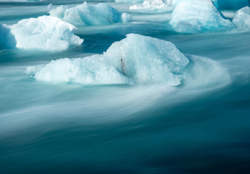 Chunks of ice floating in bright blue water of Iceland's Glacier Lagoon, long exposure