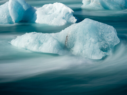 Chunks of ice floating in bright blue water of Iceland's Glacier Lagoon, long exposure