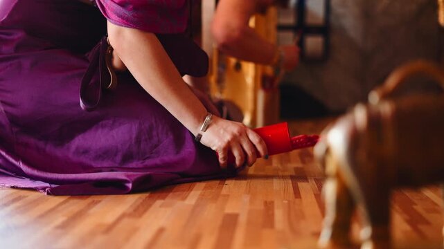 Woman kneeling drawing a red line with a fortune telling stick on a wooden floor