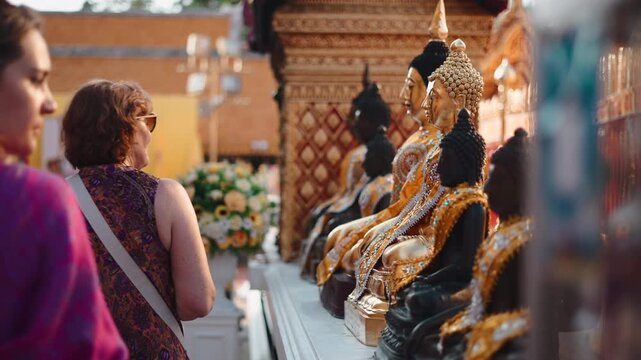Female tourists admiring buddha statues in a beautiful golden temple in southeast asia