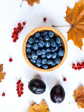 Autumn Harvest Still Life Featuring Fresh Blueberries Plums Red Currants and Maple Leaves on White Background