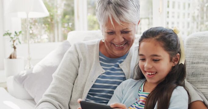 Grandmother, girl and phone in home with video call, wave goodbye or bonding together on weekend break. Happy, old woman and grandchild on sofa with tech, contact or greeting for virtual conversation