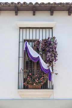 Colonial window in Antigua Guatemala decorated with purple and white drapery and flowers for Semana Santa, traditional Holy Week street decoration with copy space
