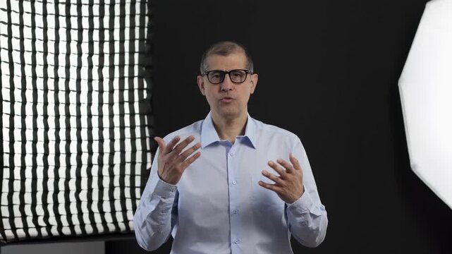 TV show, interview and man on set for filming with documentary, press or movie in studio. Recording, discussion and male journalist by lights for television public speaking with production equipment.