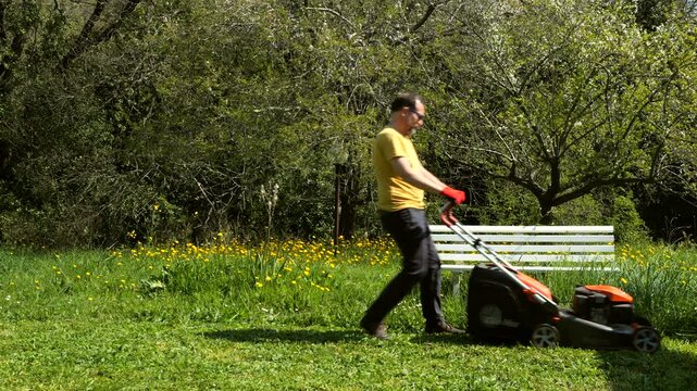 Side View Close-Up of Man Mowing Lawn in Garden