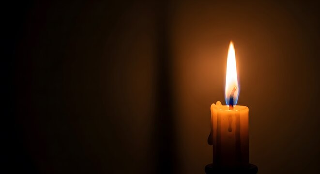 Luminous candle flame on a dark, empty background. Ideal for bereavement concepts, spiritual meditation, and honor of the deceased with plenty of text space