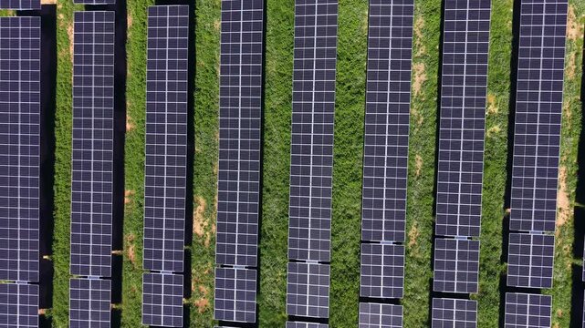 Top-down aerial of utility-scale photovoltaic array with parallel panel rows, DC strings and access corridors, illustrating high-density solar generation and land-use optimization