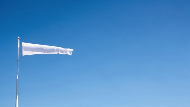 White fabric windsock on a metal pole against a blue sky in horizontal framing.