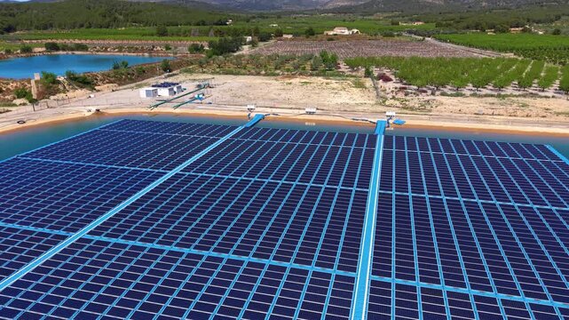 Aerial view of floating solar farm with modular HDPE pontoons, anchored arrays, DC cabling corridors and service walkways on irrigation reservoir, enabling efficient solar generation